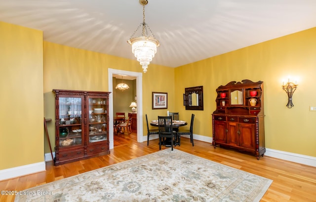 dining area with baseboards, wood finished floors, and a chandelier