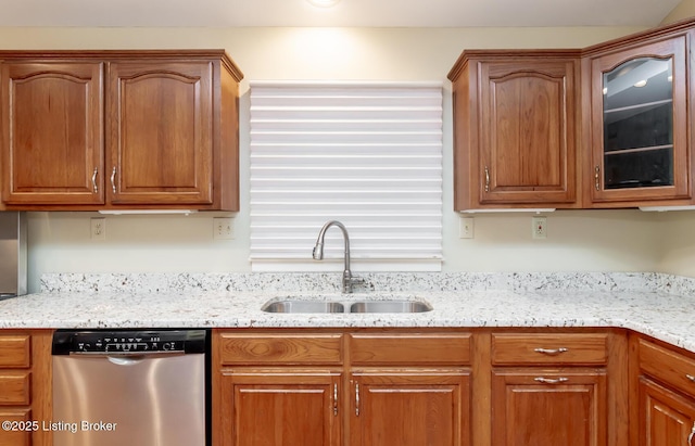 kitchen with light stone counters, dishwasher, glass insert cabinets, and a sink