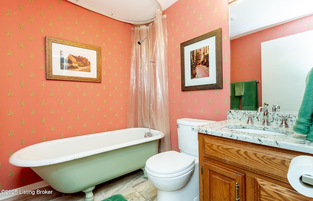 bathroom with wallpapered walls, a freestanding tub, toilet, and vanity