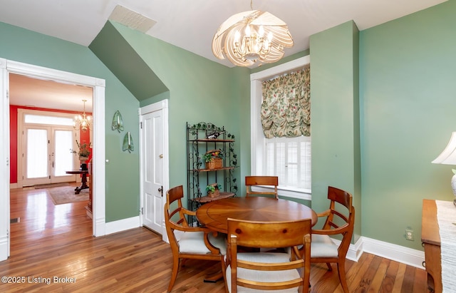 dining room with a chandelier, visible vents, baseboards, and wood finished floors