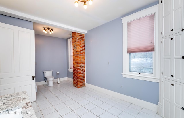 bathroom with baseboards, toilet, and tile patterned flooring