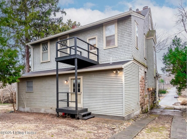 view of front of home featuring a chimney and a balcony