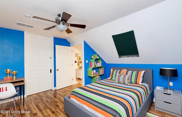 bedroom with wood finished floors, visible vents, ceiling fan, vaulted ceiling, and connected bathroom