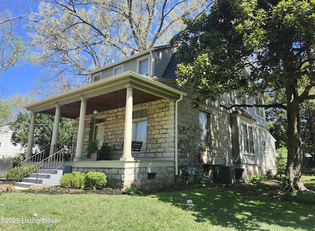 view of front facade with a front yard, a porch, and stone siding