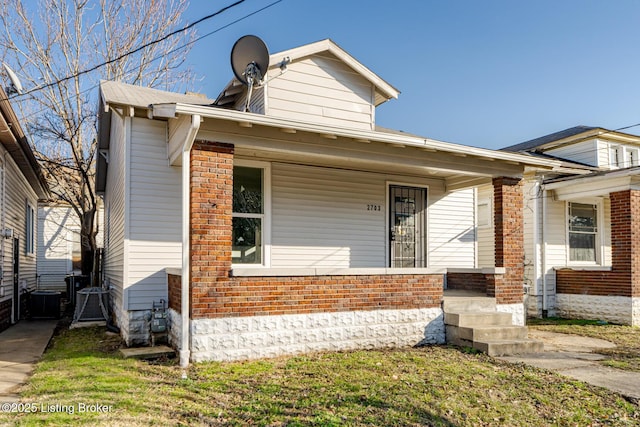 view of front facade featuring a porch, central air condition unit, and brick siding