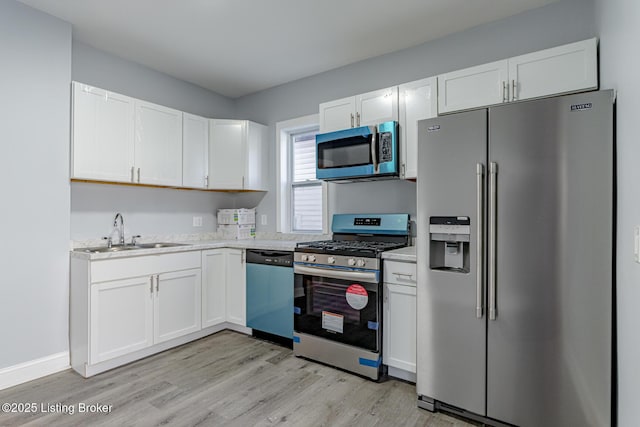 kitchen with white cabinets, appliances with stainless steel finishes, light countertops, and a sink