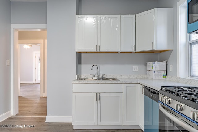 kitchen featuring white cabinetry, dishwashing machine, light wood-style flooring, and a sink