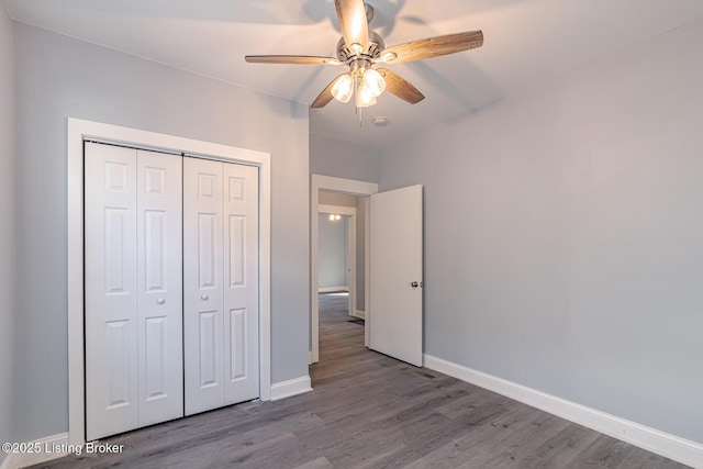 unfurnished bedroom featuring a closet, baseboards, wood finished floors, and a ceiling fan