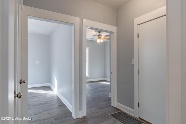 hallway with visible vents, baseboards, and wood finished floors