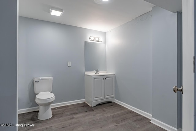 half bath featuring toilet, vanity, baseboards, and wood finished floors