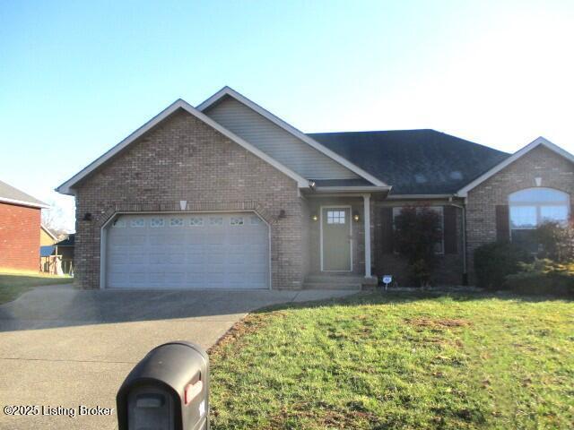 ranch-style home with brick siding, an attached garage, concrete driveway, and a front yard