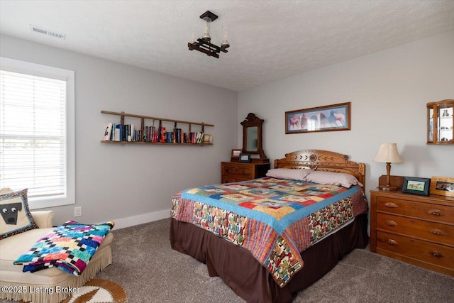 carpeted bedroom featuring visible vents, baseboards, and a textured ceiling