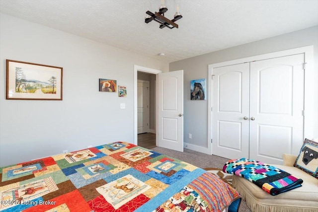 carpeted bedroom featuring baseboards, a closet, and a textured ceiling