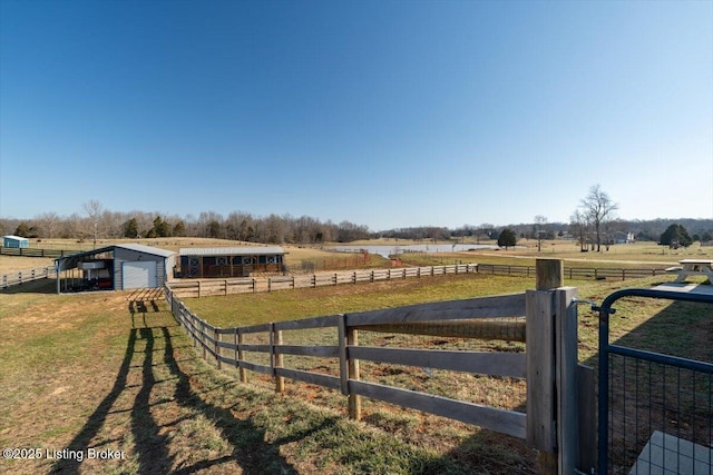 view of yard with an outbuilding, a rural view, a pole building, and fence