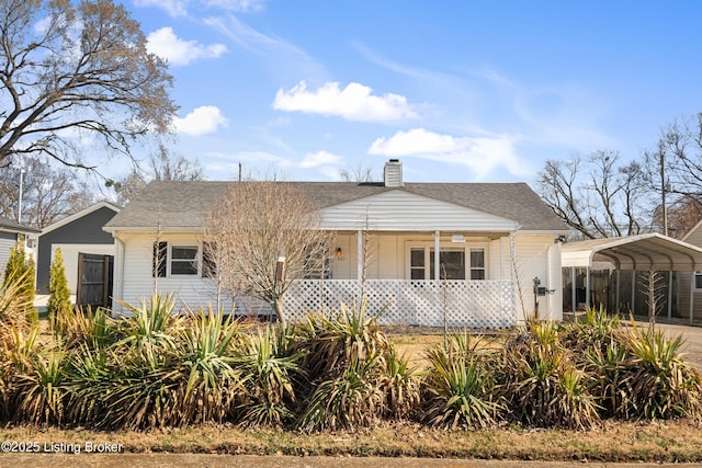 view of front of property with a carport, covered porch, a chimney, and roof with shingles