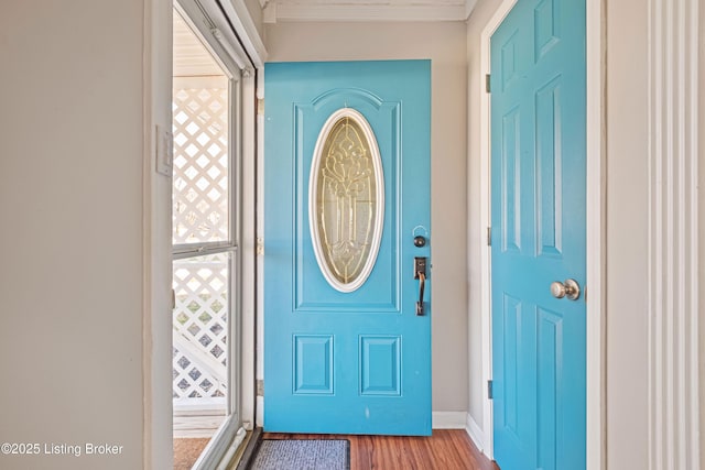 entrance foyer with crown molding, baseboards, and wood finished floors