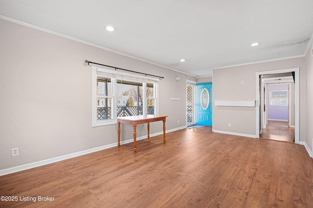 unfurnished living room with baseboards, plenty of natural light, crown molding, and light wood finished floors