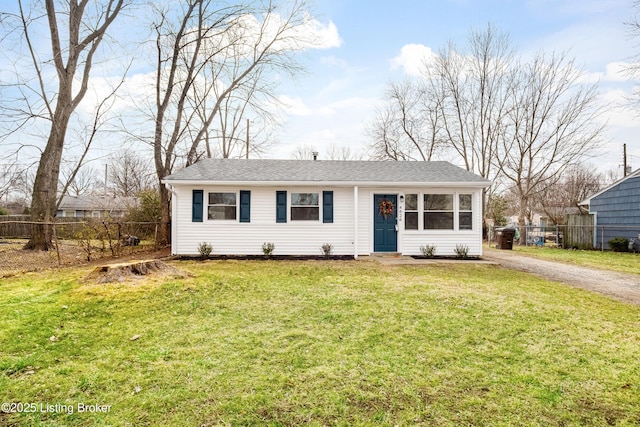 ranch-style home featuring driveway, a shingled roof, a front yard, and fence