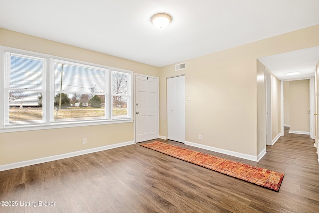 empty room with visible vents, baseboards, and wood finished floors