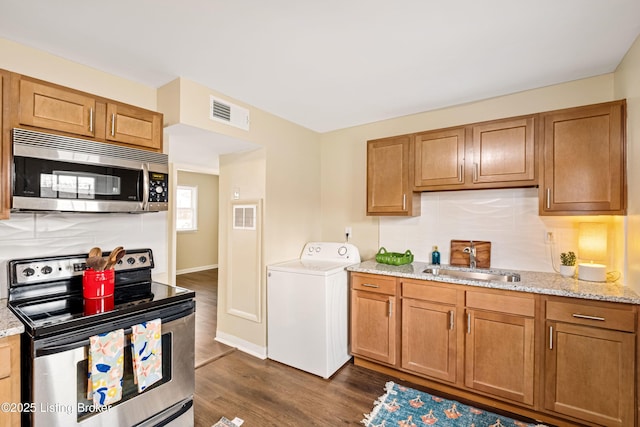 kitchen with dark wood-style floors, visible vents, washer / clothes dryer, a sink, and appliances with stainless steel finishes