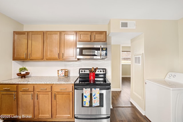 kitchen featuring visible vents, light stone countertops, washer / dryer, dark wood-style floors, and stainless steel appliances