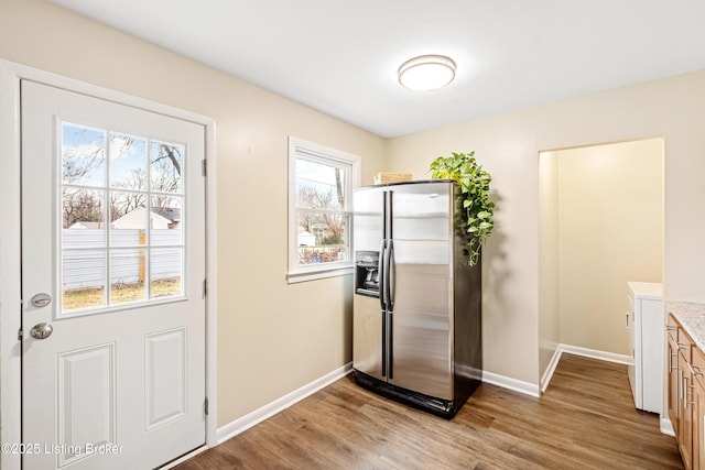 kitchen with light countertops, light wood-style flooring, stainless steel fridge with ice dispenser, and baseboards