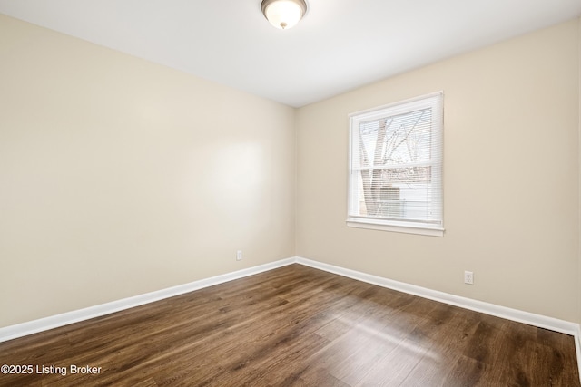 empty room with baseboards and dark wood-type flooring