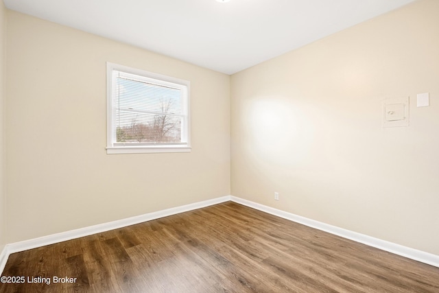 spare room with baseboards and wood finished floors