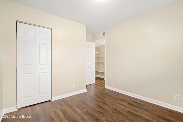 unfurnished bedroom with visible vents, baseboards, and dark wood-style flooring