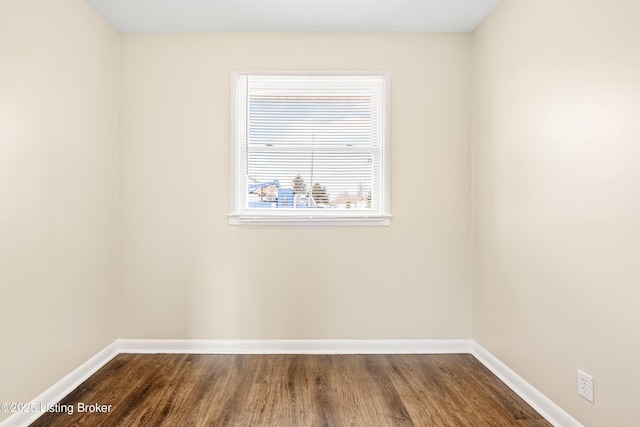 empty room with baseboards and dark wood-type flooring