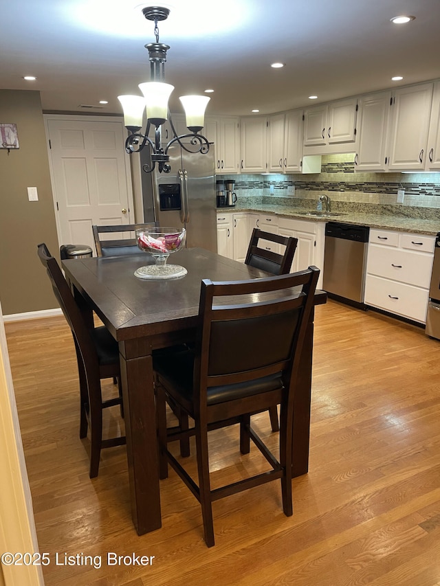 dining space featuring recessed lighting, baseboards, an inviting chandelier, and light wood finished floors