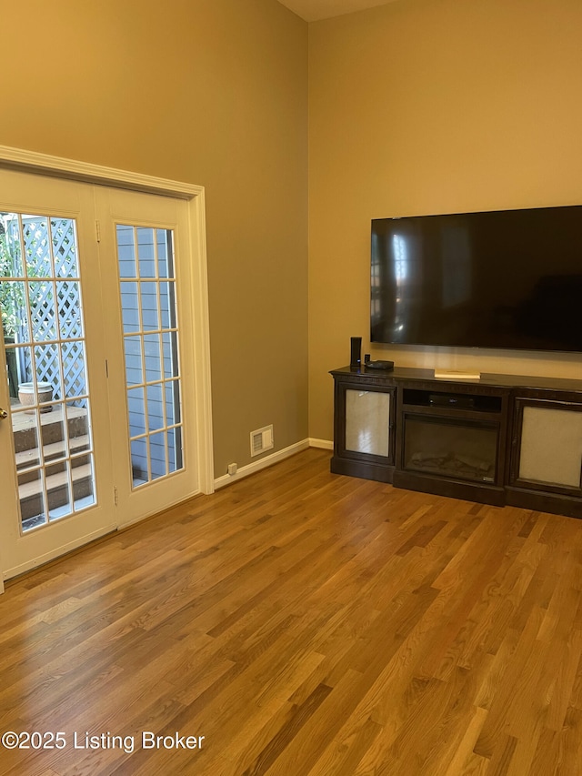 unfurnished living room with visible vents, baseboards, and wood finished floors