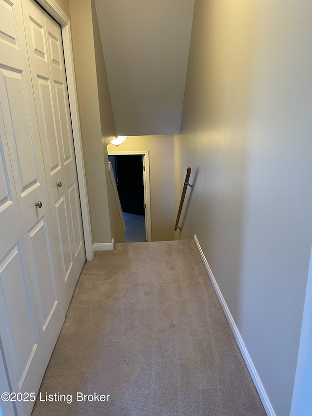 hall with baseboards, an upstairs landing, and carpet floors