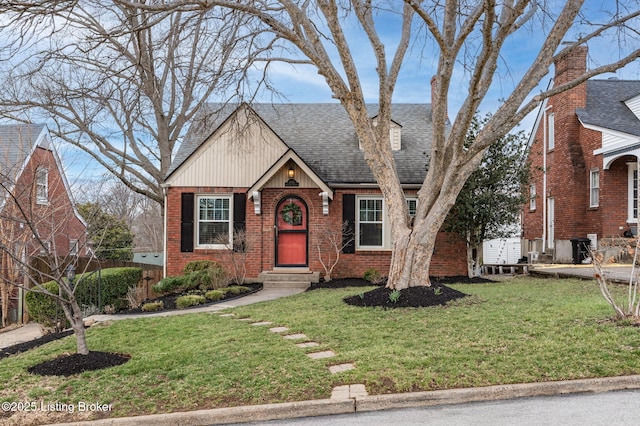 view of front of home with brick siding, roof with shingles, a front yard, and entry steps