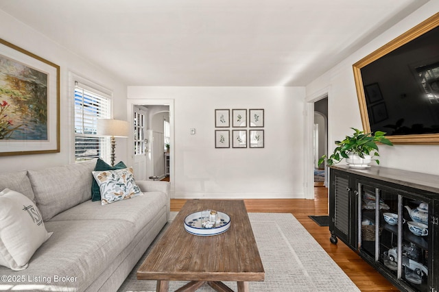 living room with wood finished floors, arched walkways, and baseboards