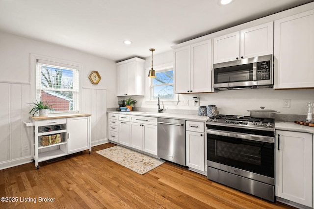 kitchen featuring a sink, white cabinetry, light wood-style floors, appliances with stainless steel finishes, and light countertops