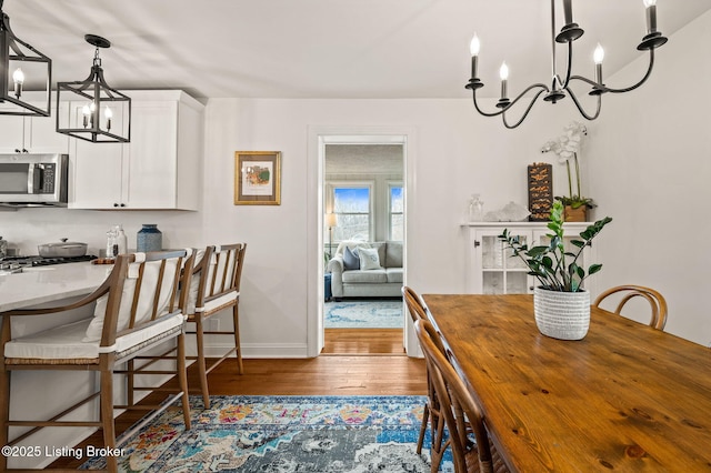 dining space featuring a notable chandelier, wood finished floors, and baseboards