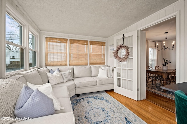 living area with a textured ceiling, wood finished floors, and a chandelier