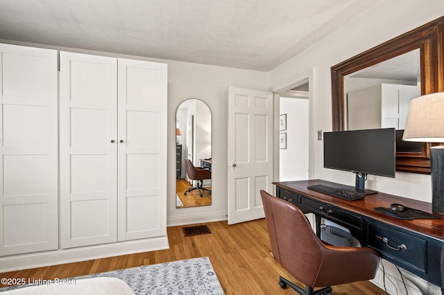 office space with visible vents, arched walkways, light wood-style floors, and baseboards