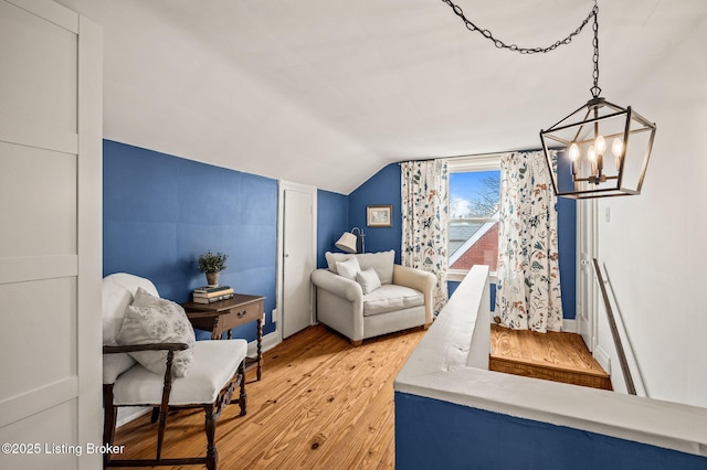 interior space with vaulted ceiling, a notable chandelier, wood finished floors, and baseboards