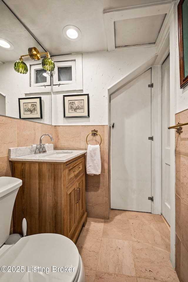 bathroom featuring toilet, tile walls, and vanity