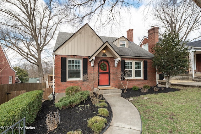 view of front of property with a shingled roof, fence, brick siding, and a chimney