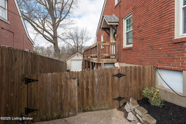 view of home's exterior featuring brick siding, a gate, an outdoor structure, and fence