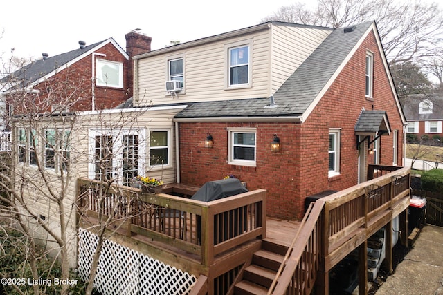 back of house featuring cooling unit, brick siding, roof with shingles, and a deck