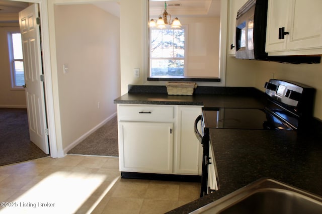 kitchen with a healthy amount of sunlight, white cabinets, electric stove, stainless steel microwave, and light colored carpet