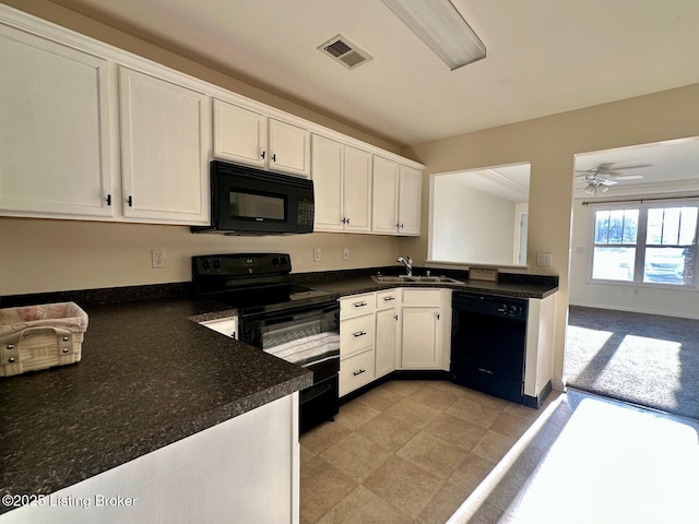 kitchen with visible vents, white cabinetry, black appliances, and a sink