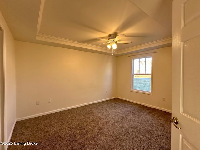 unfurnished room with ornamental molding, a tray ceiling, dark carpet, baseboards, and ceiling fan