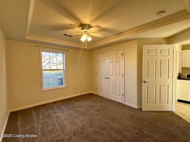 unfurnished bedroom featuring visible vents, crown molding, baseboards, carpet flooring, and a raised ceiling