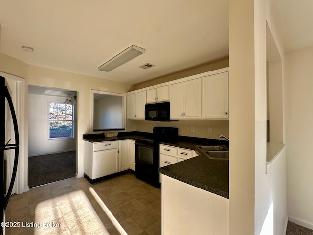 kitchen featuring visible vents, black appliances, a sink, dark countertops, and white cabinetry