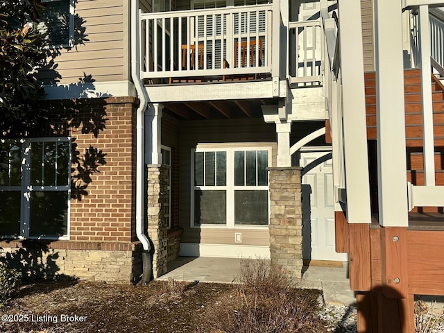 exterior space featuring a balcony and brick siding